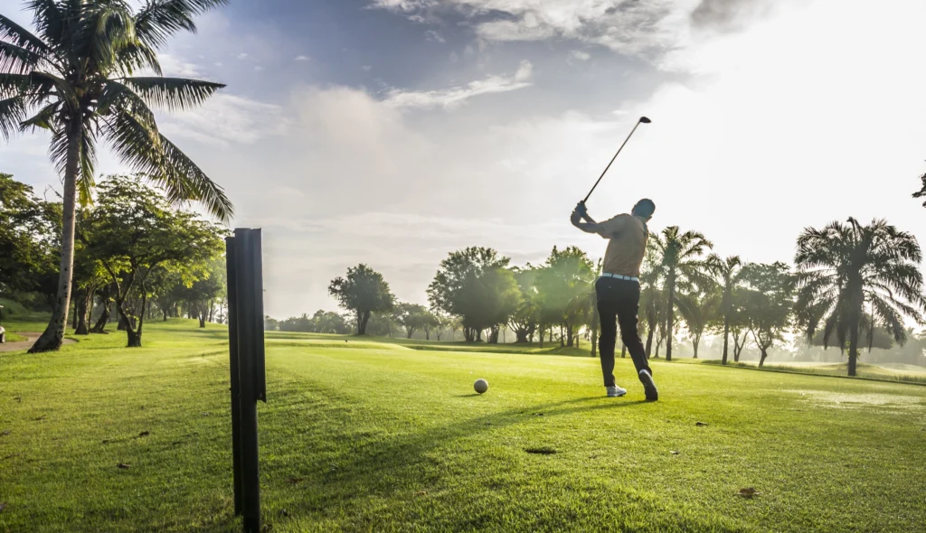 Golfer teeing off at sunrise